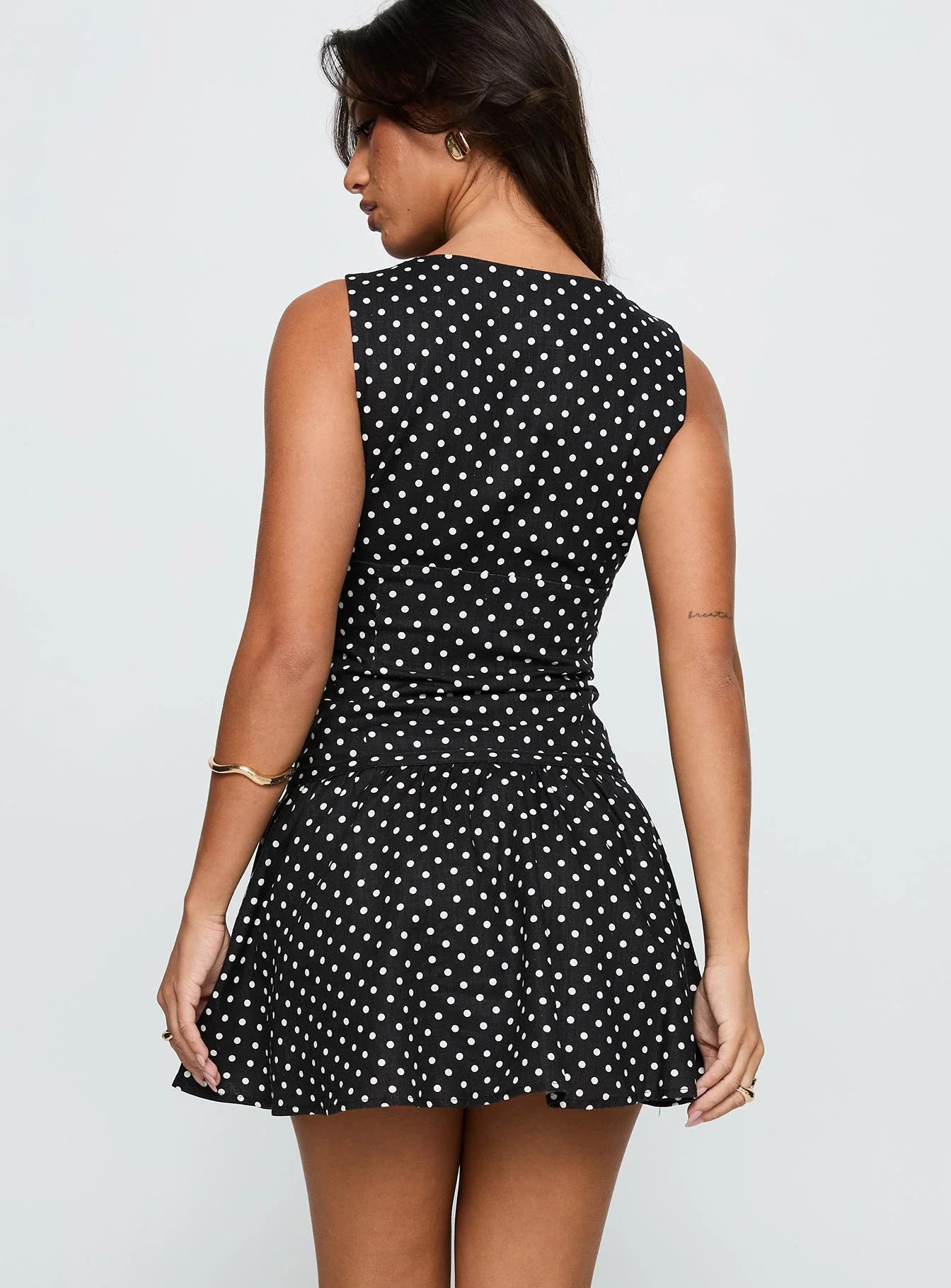 Side view of ruched A-line polka dot mini dress.