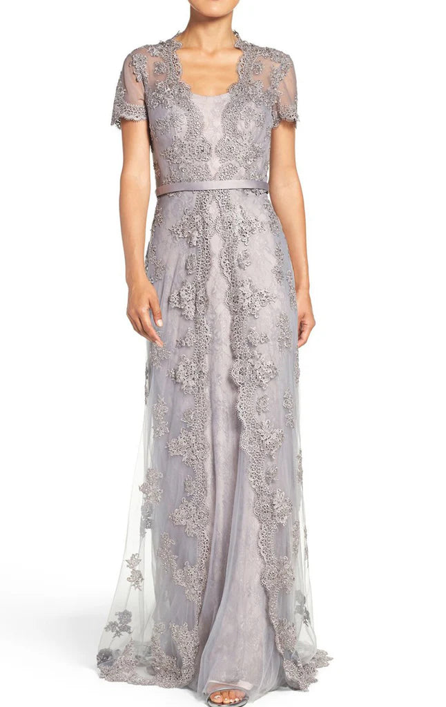 Woman wearing an elegant A-line lace short sleeve formal dress, posing gracefully.