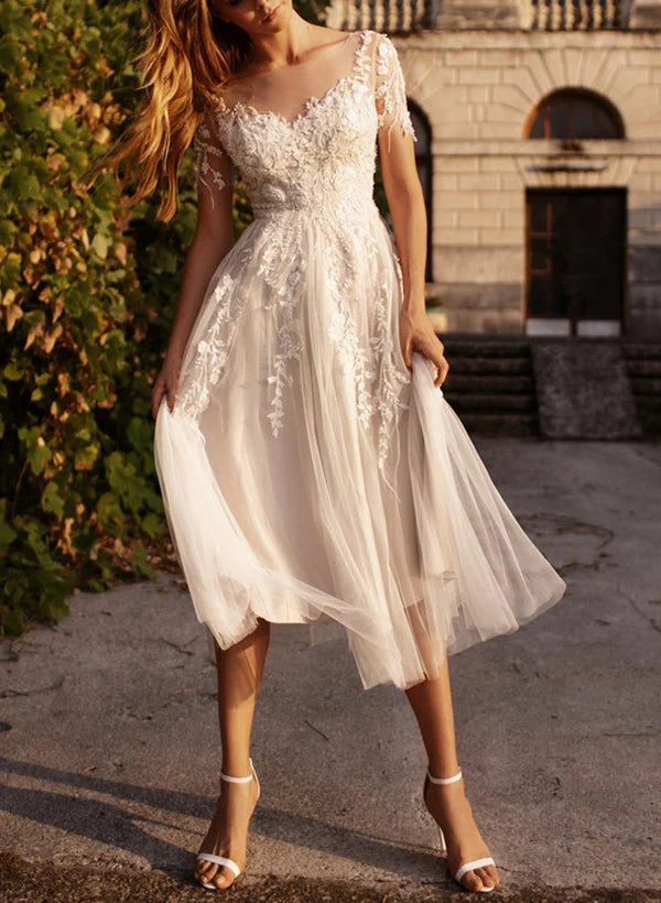Full length view of a bride in an A-line wedding dress with delicate lace appliques.