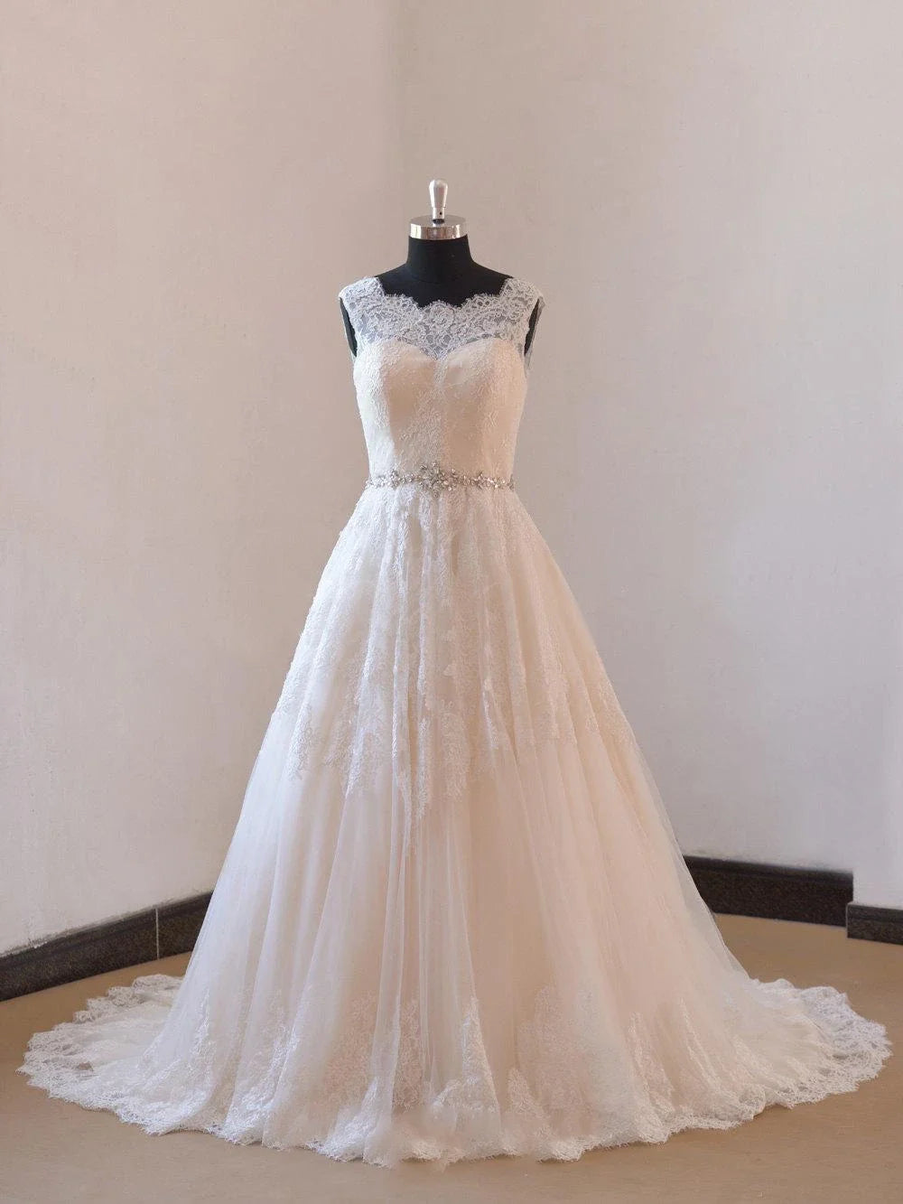 Full view of an elegant A-line lace wedding dress with an illusion neckline.