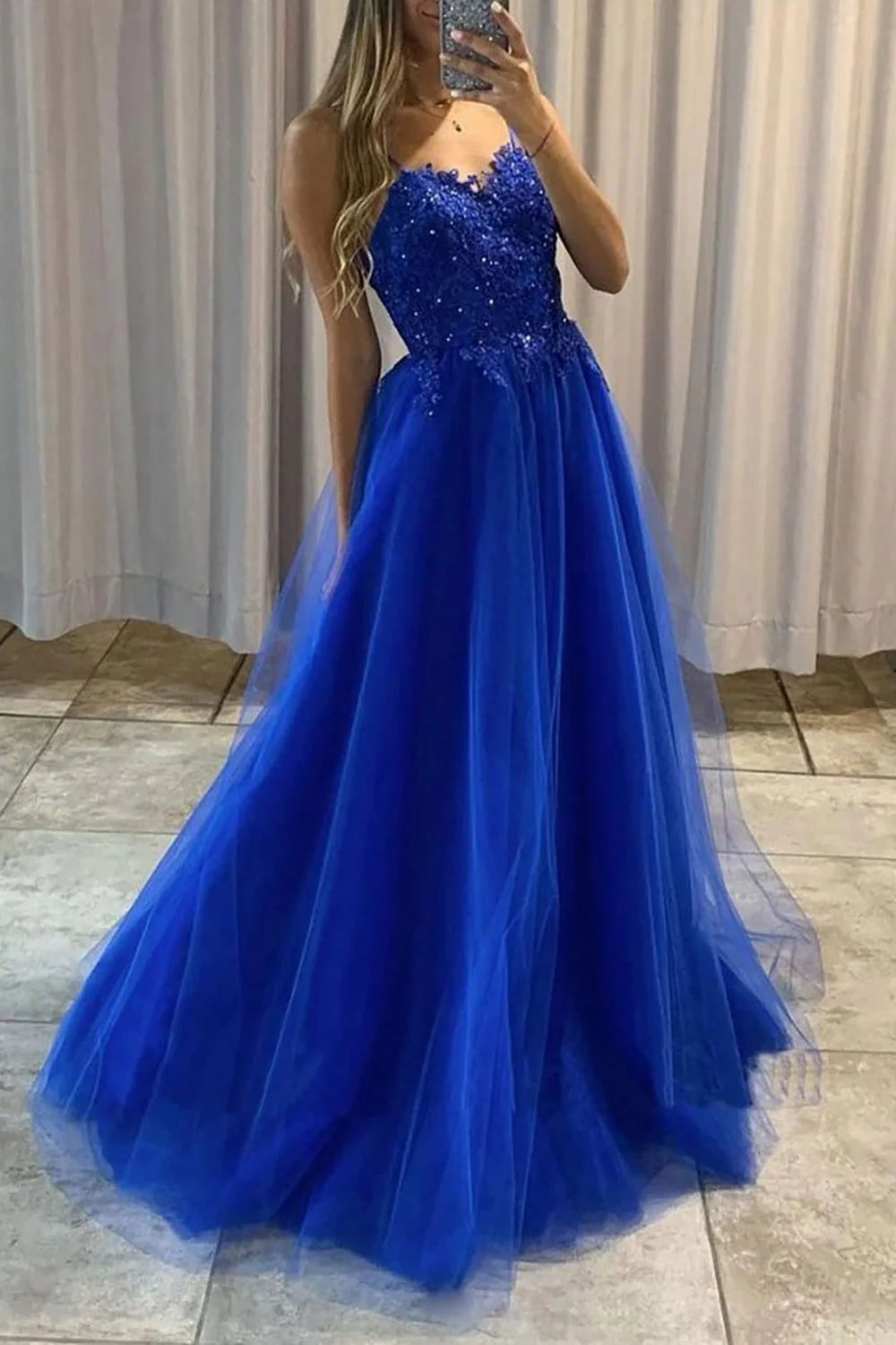 Model wearing an elegant A-line long prom dress with spaghetti straps and intricate beading.