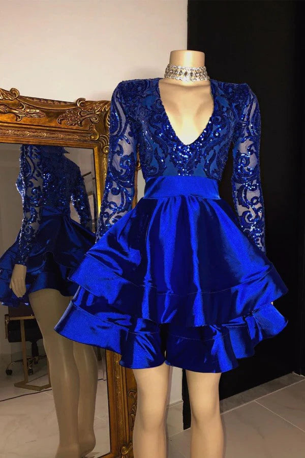 Model wearing a royal blue A-line homecoming dress with long sequin sleeves and a tiered satin skirt.