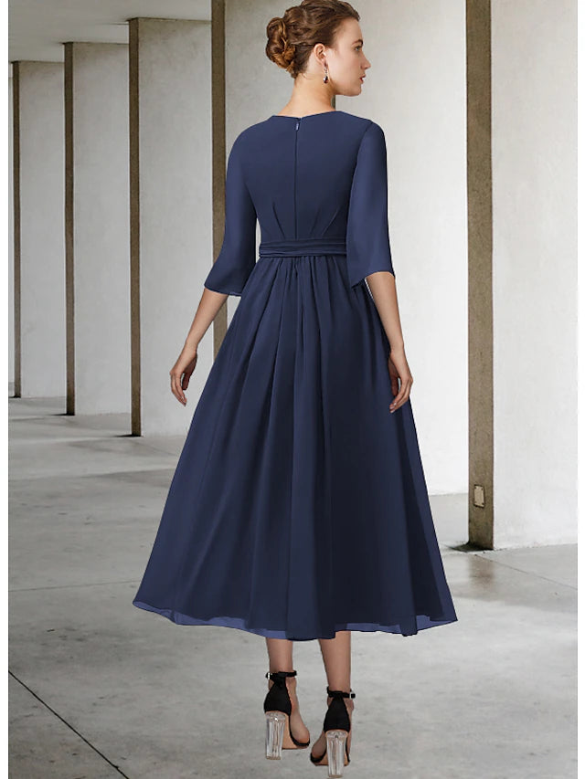 Full view of the tea length A-Line dress, showcasing pleats and a sash detail.