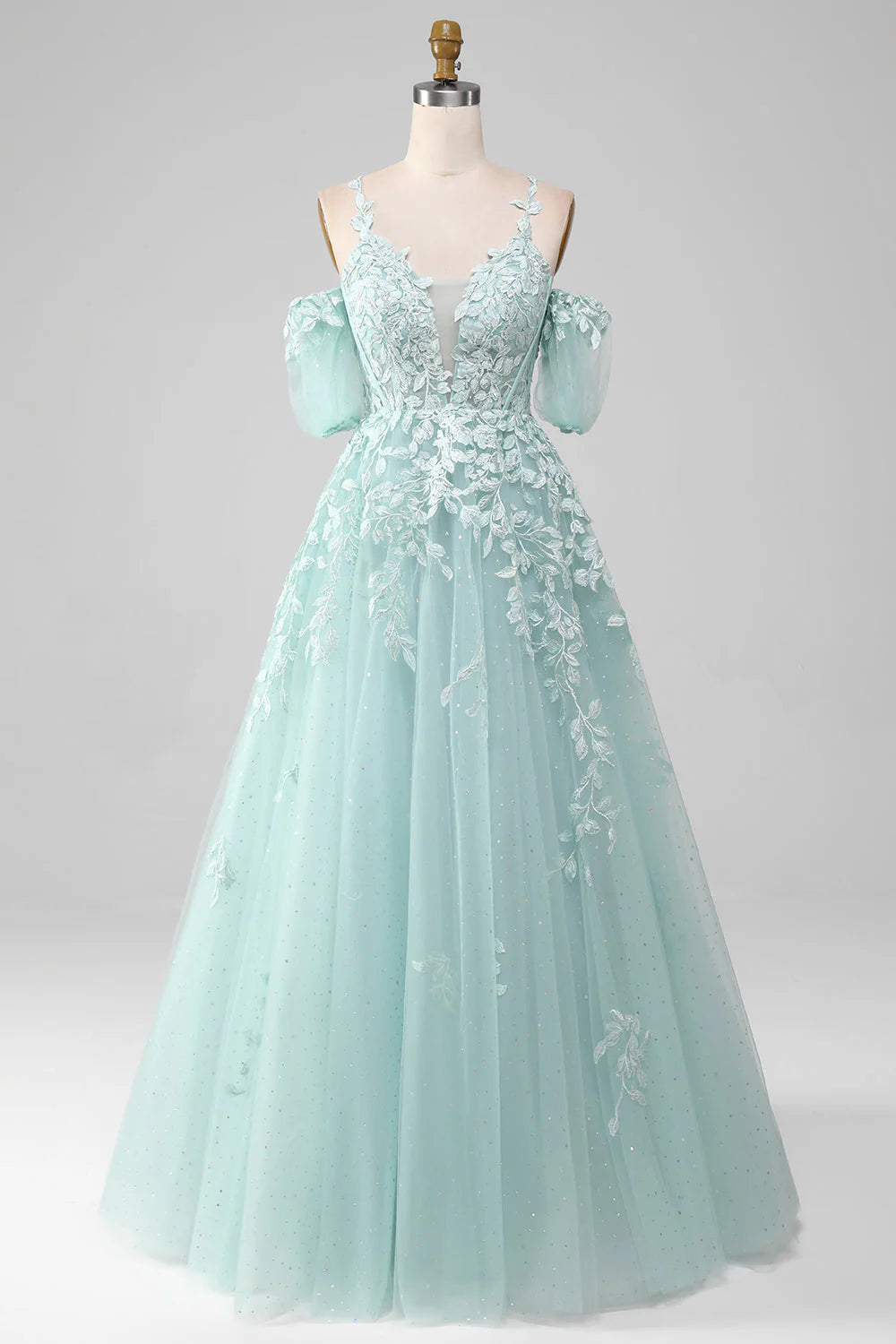 Model wearing an elegant mint green off-shoulder prom dress with intricate beading and appliques.