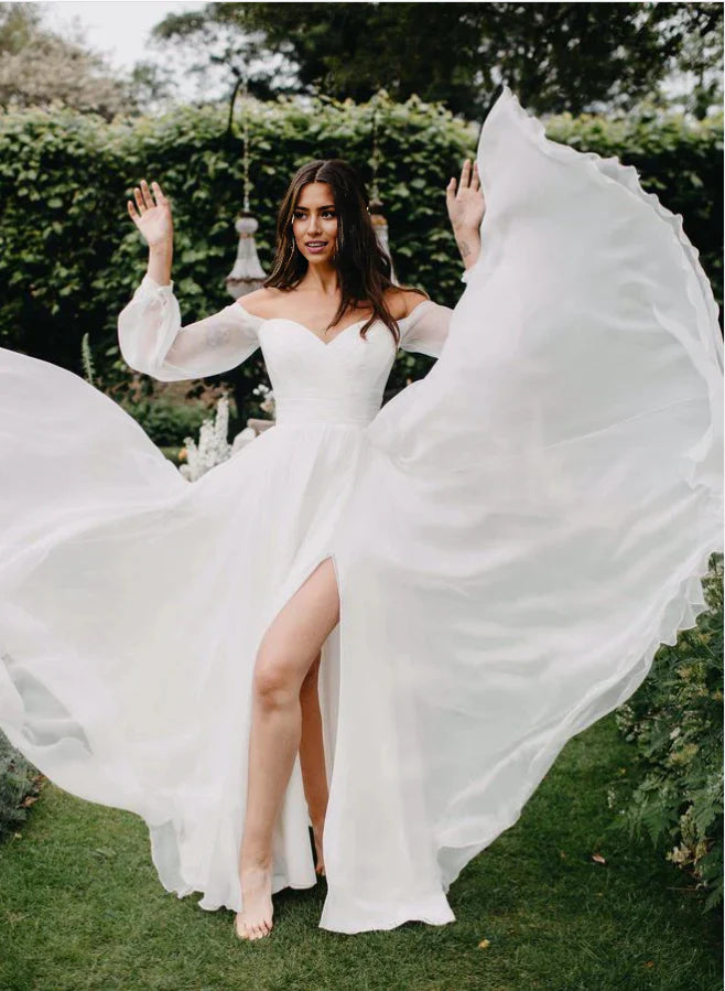 Elegant A-line off-the-shoulder chiffon wedding dress with long sleeves and a thigh-high slit.