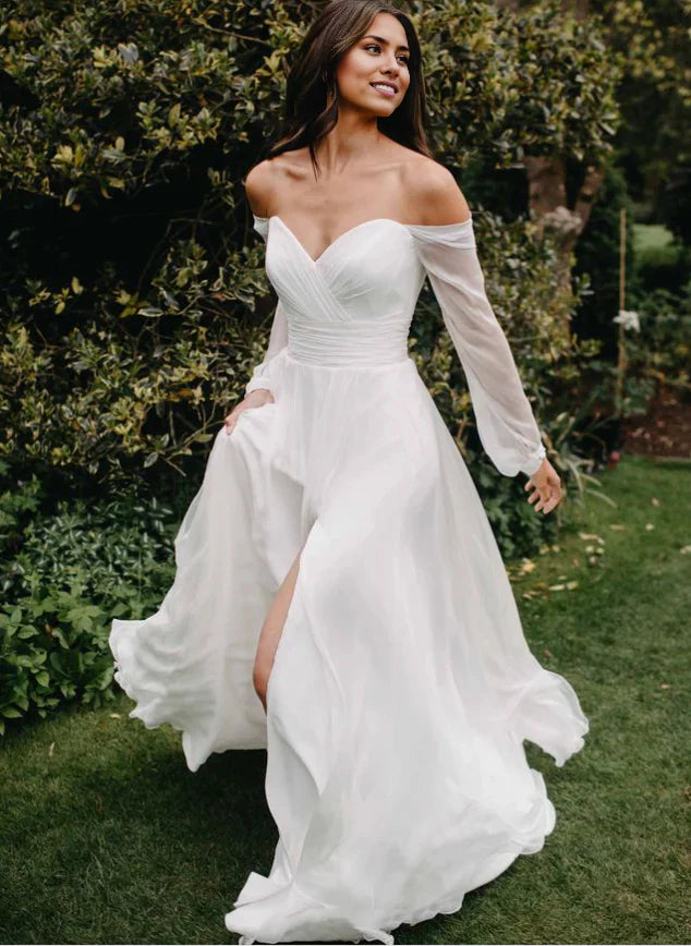 Bride wearing a flowing A-line off-shoulder long sleeve wedding gown with a side slit.
