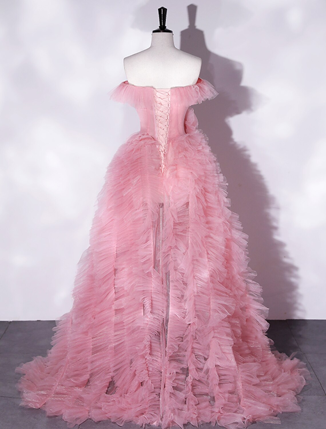 Side view of a woman in an A-line off-shoulder floral tulle maxi dress, showcasing the asymmetrical design.