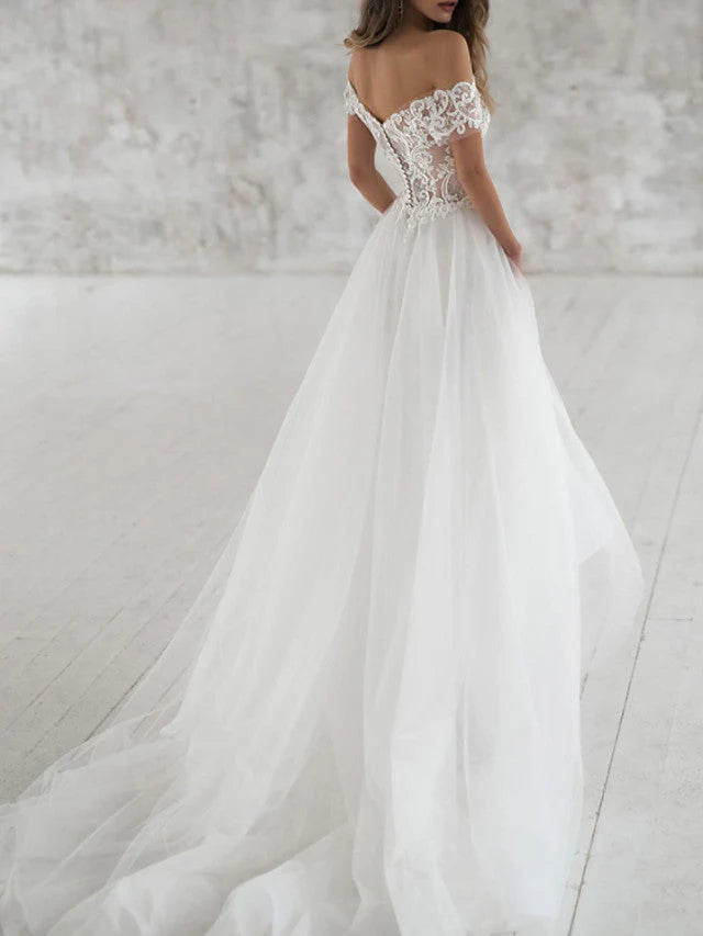 Back view of a long lace and tulle wedding gown, perfect for a beach ceremony.