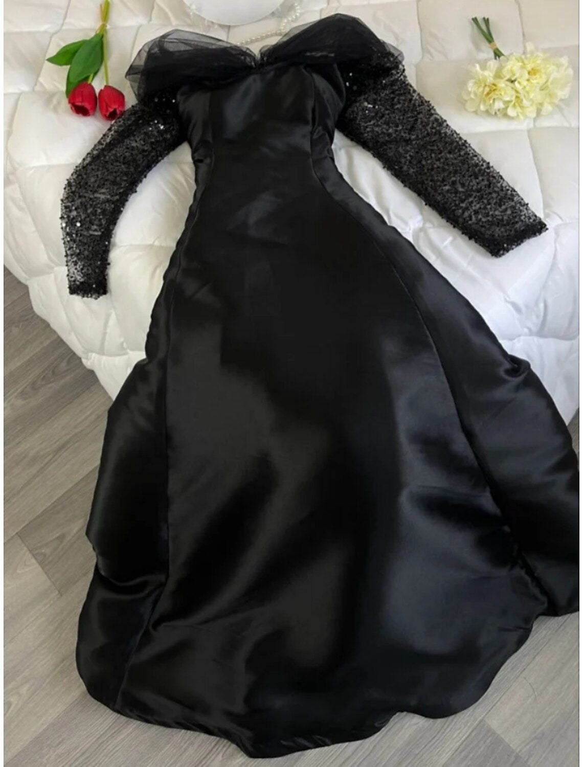 Elegant A-line off-shoulder black satin evening gown with long sleeves and sequin details.