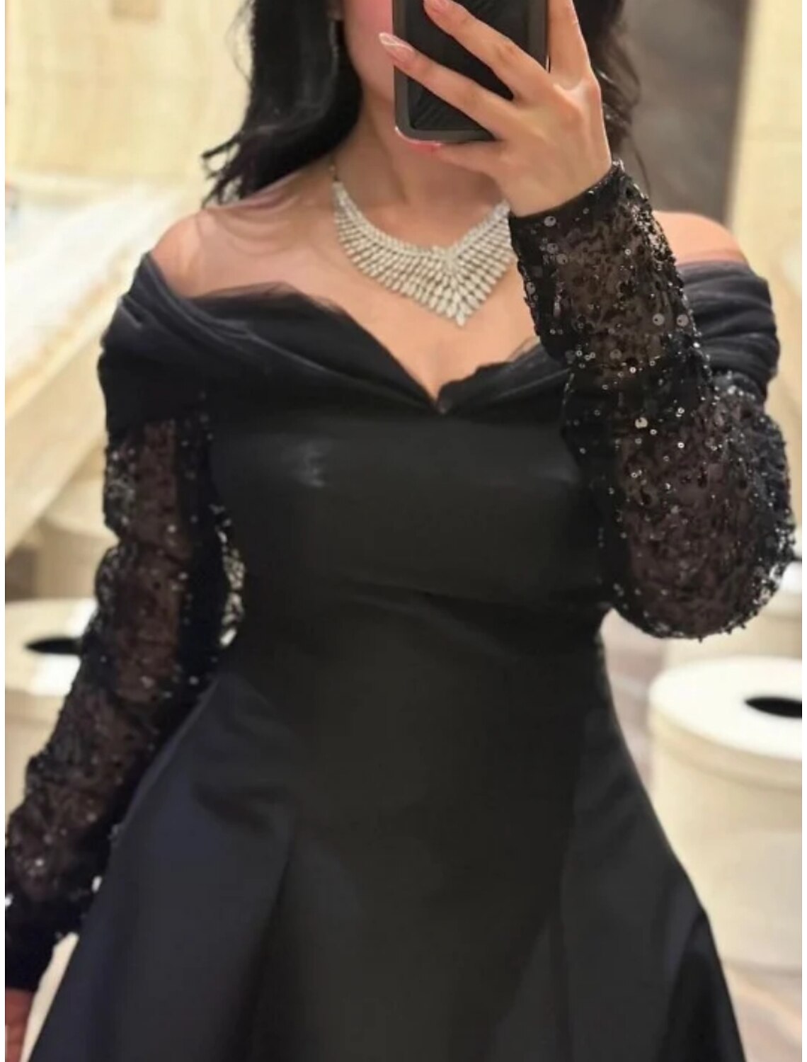 Back view of the A-line black formal dress showing pleats and floor-length design.