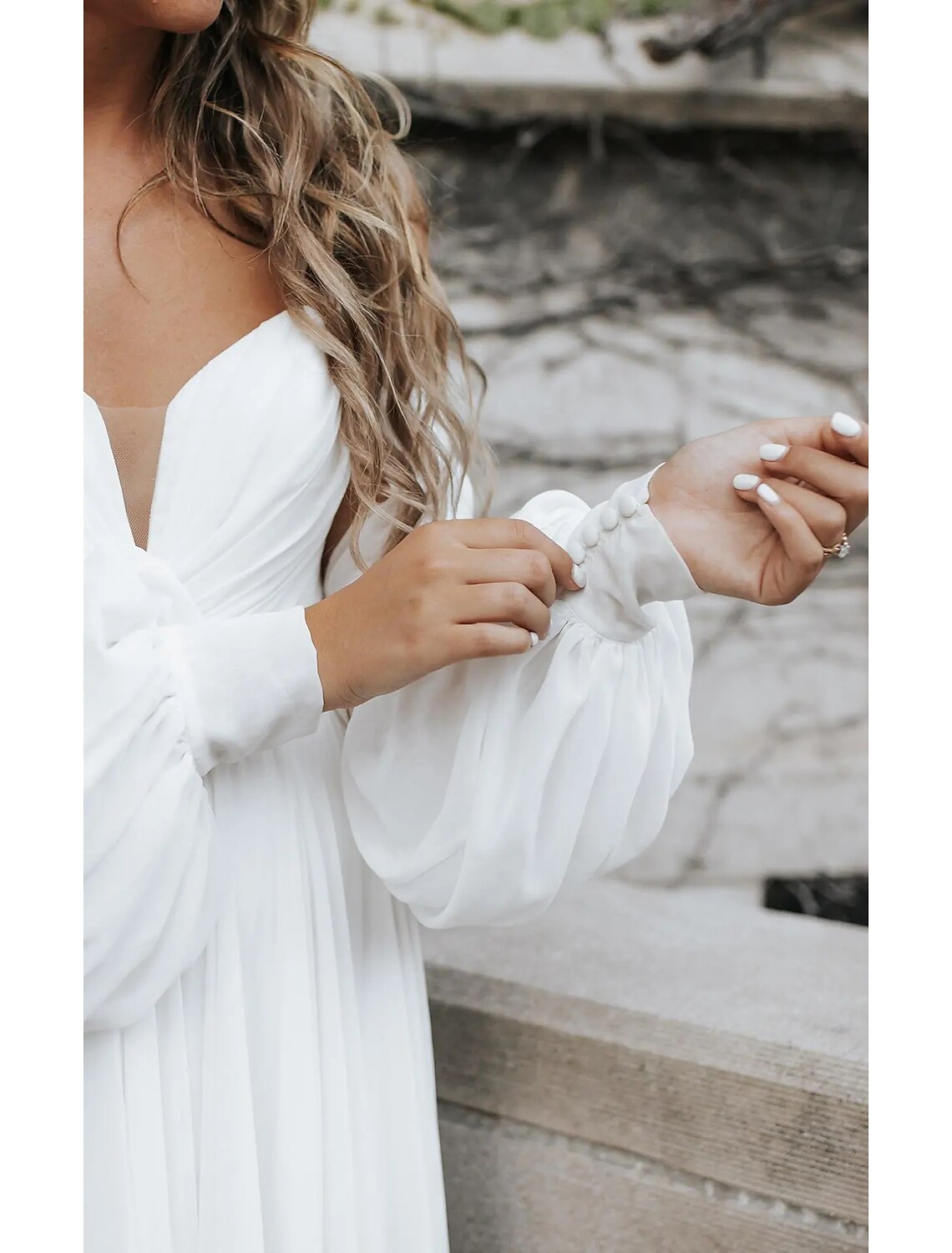 Model walking on the beach, showcasing the flowy chiffon and split front of the wedding dress.