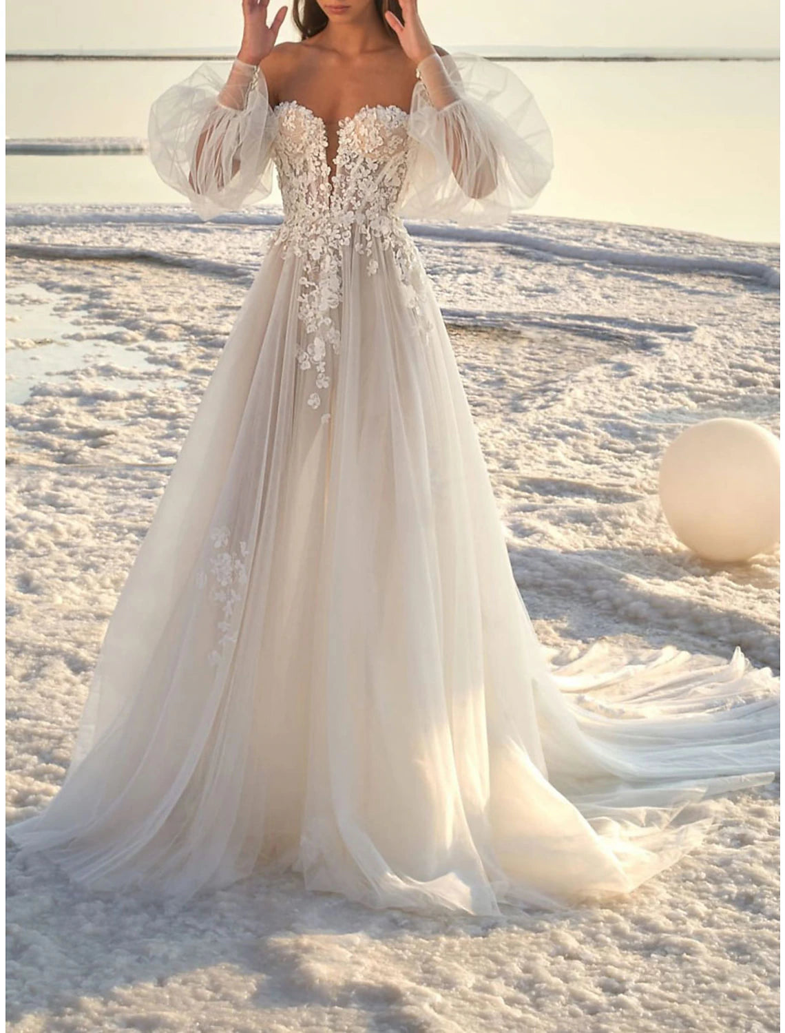 Close-up of the off-shoulder neckline and long lace sleeves on a wedding dress.