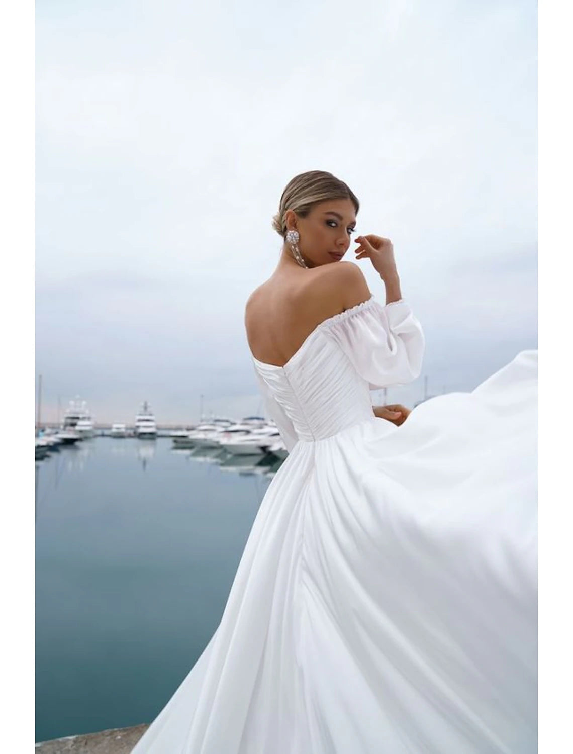 Back view of an A-line off-shoulder long sleeve chiffon bridal gown with sweep train.