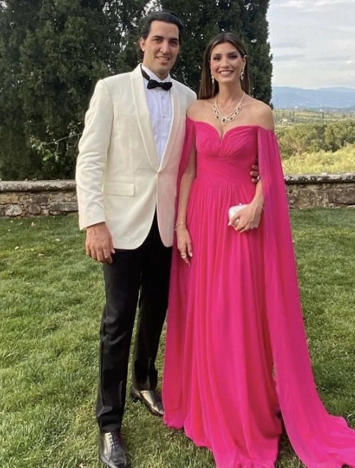 Woman wearing an elegant A-line off-shoulder chiffon gown in a light color.