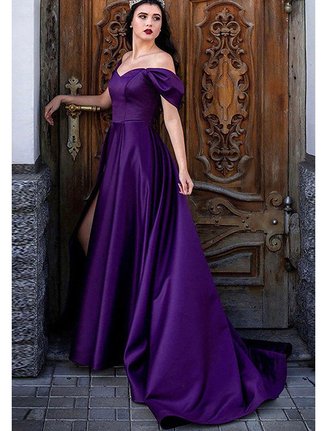 Model wearing an elegant A-line off-shoulder satin prom dress with pleats, a high slit, and a sweep train.