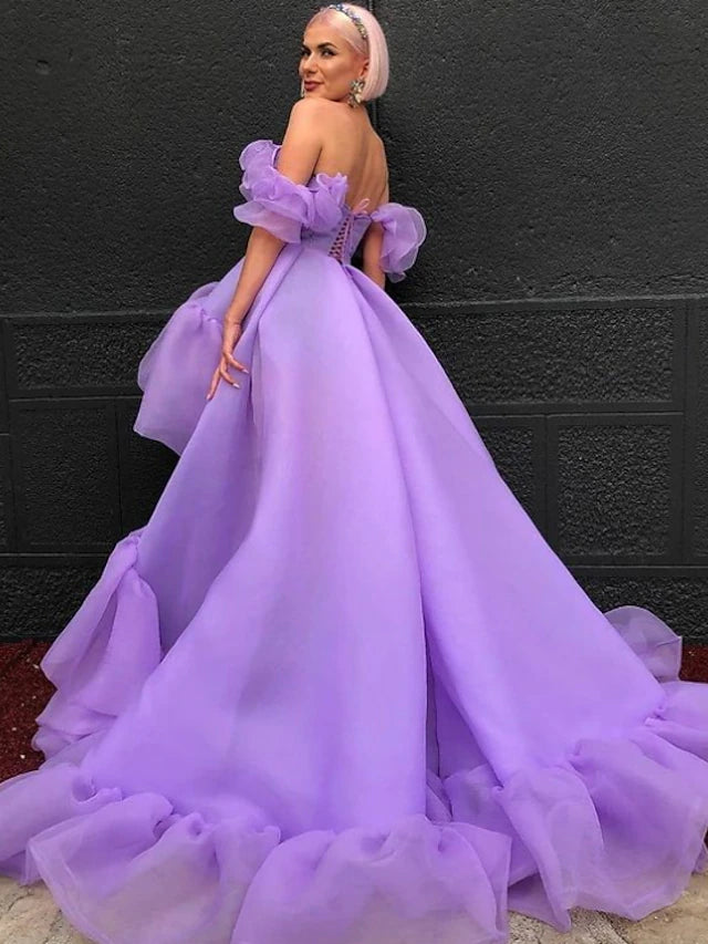 Back view of purple A-line high-low prom dress, highlighting tiered tulle skirt.