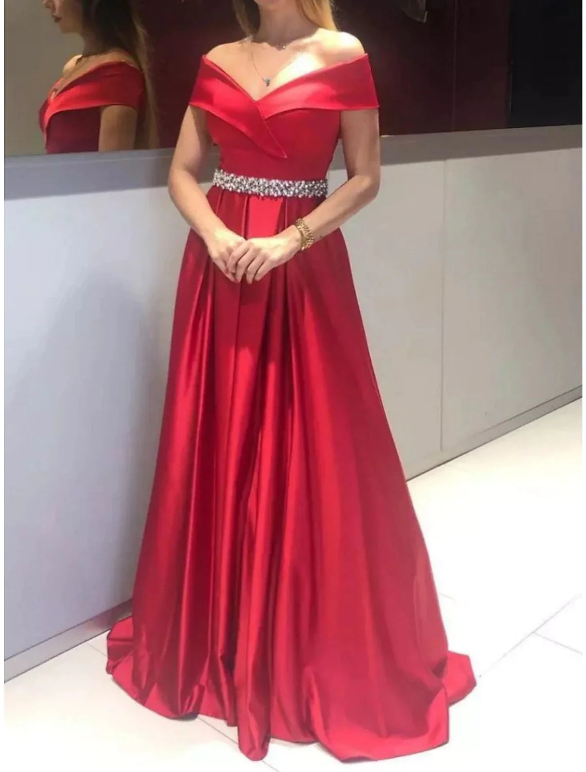 Close-up of the off-shoulder neckline and crystal embellishments on the red gown.