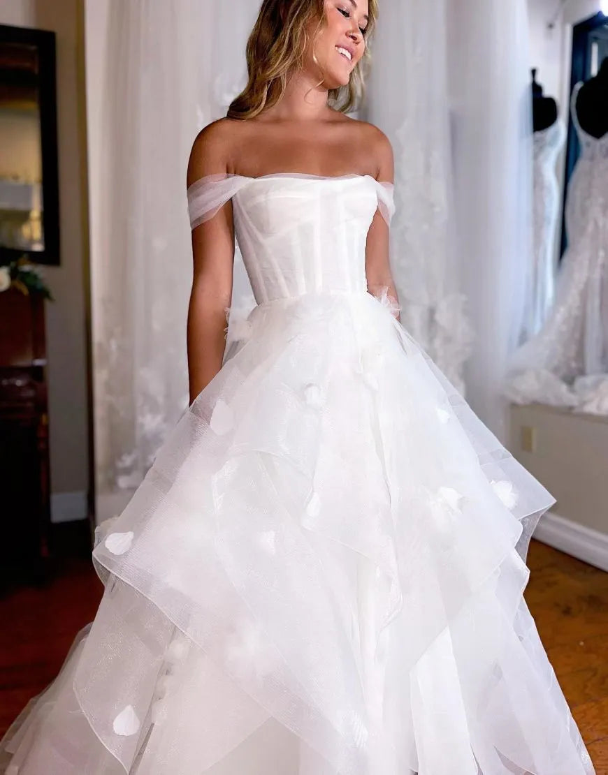 Side view of white A-line off-shoulder bridal gown with flowing skirt.