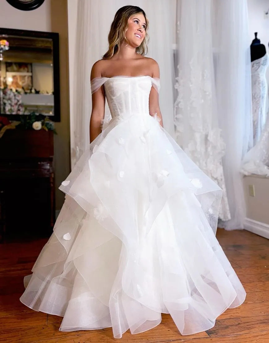 Back view of white off-shoulder wedding dress, showcasing ruffles and train.