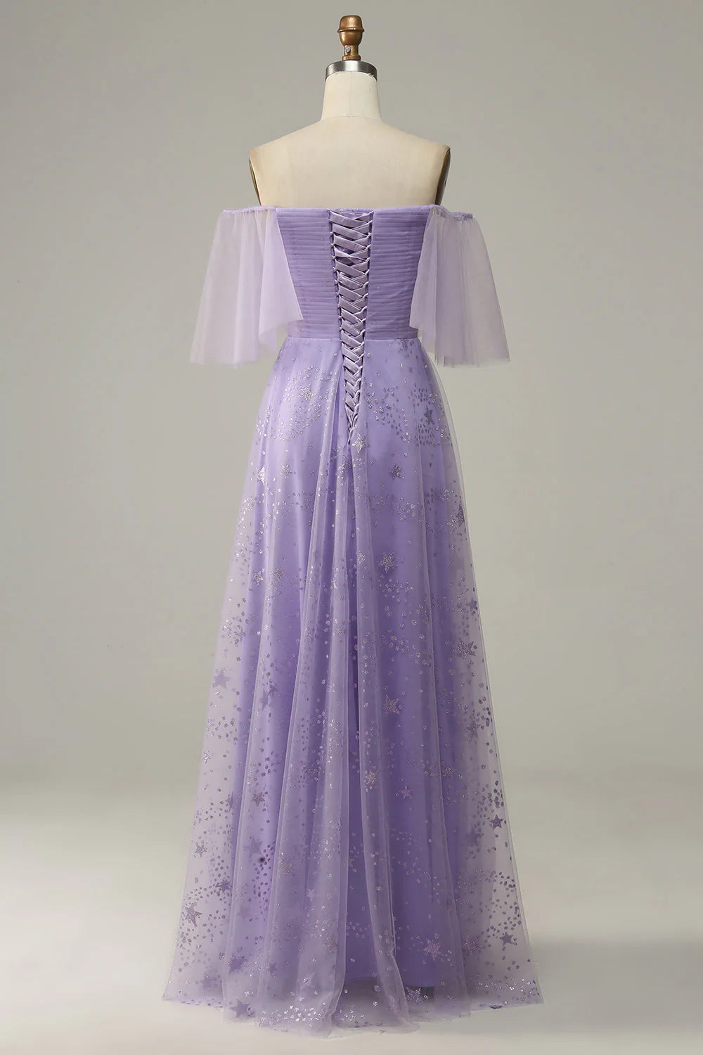 Model wearing a purple off-shoulder ruffled prom dress, side view.