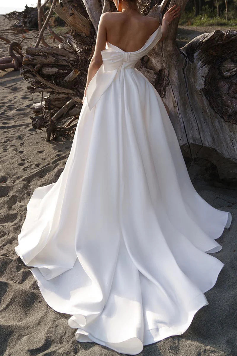 Close-up of the off-shoulder Bardot neckline and pleated satin fabric of the wedding dress.