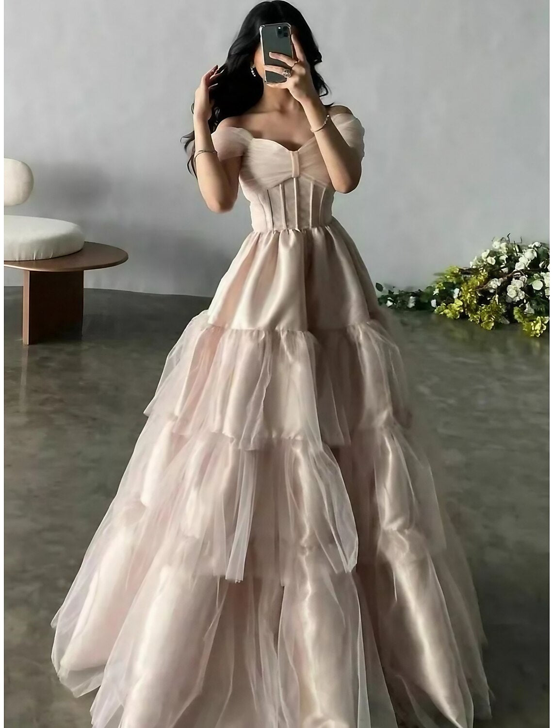 Woman wearing an elegant A-line off-shoulder short sleeve dusty blue satin gown with pleats.