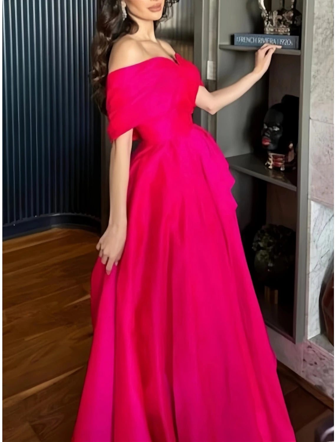 Side view of red A-line off-shoulder satin evening gown with pleats.