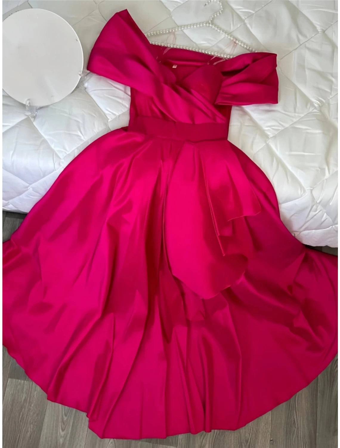 Close-up of off-shoulder neckline and satin fabric on red evening gown.