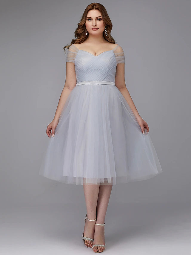 Side view of a model wearing an A-line off-shoulder tea length tulle dress, highlighting the short sleeves.