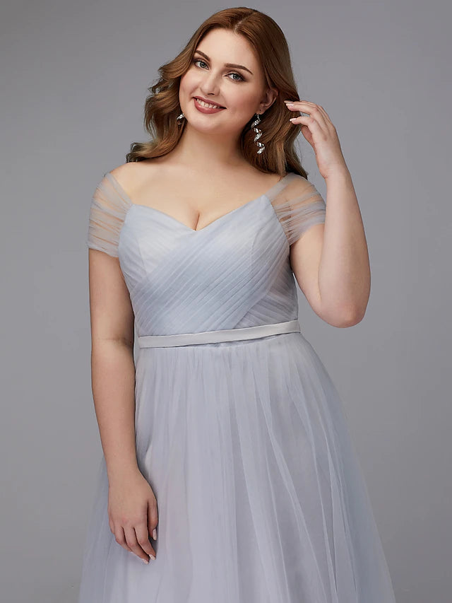 Detail of the criss-cross sash and flowing tea length skirt of the tulle dress.