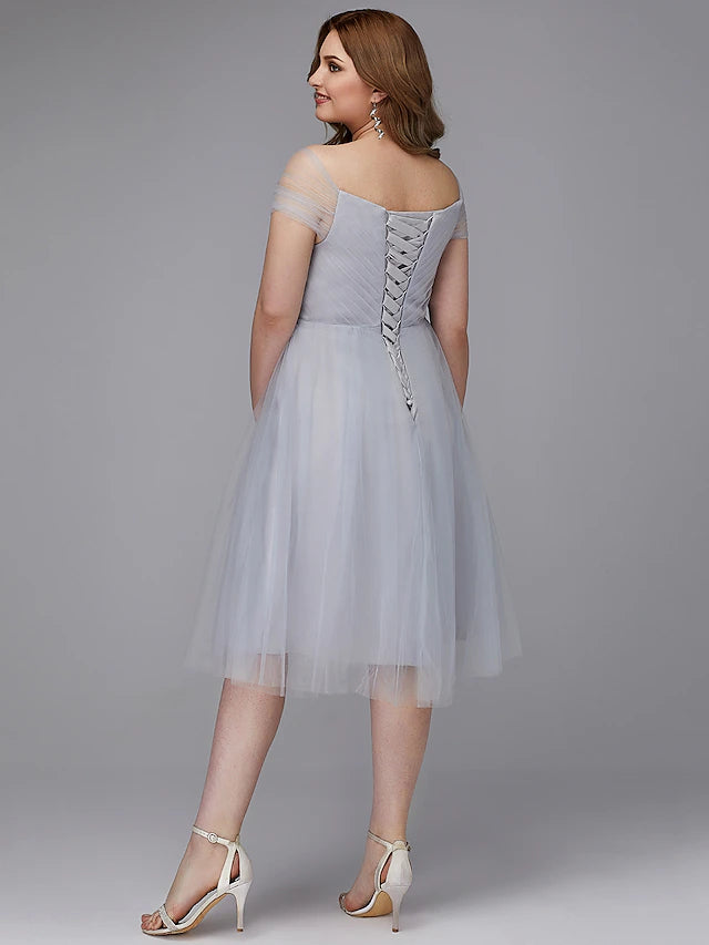 Model in an A-line off-shoulder tea length tulle dress, captured in a dynamic pose.