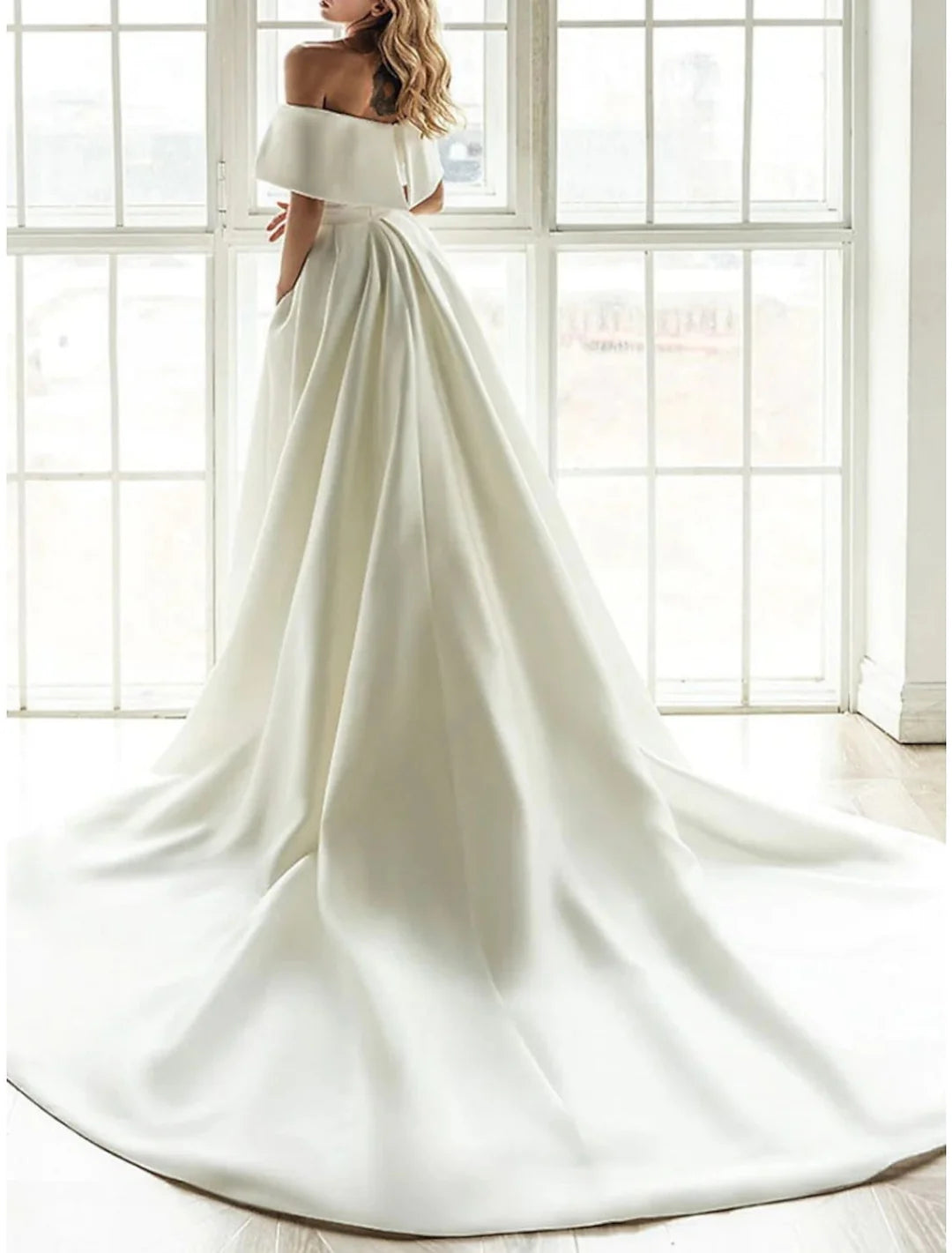 Side view of a model in an A-line off-the-shoulder floor-length wedding dress.