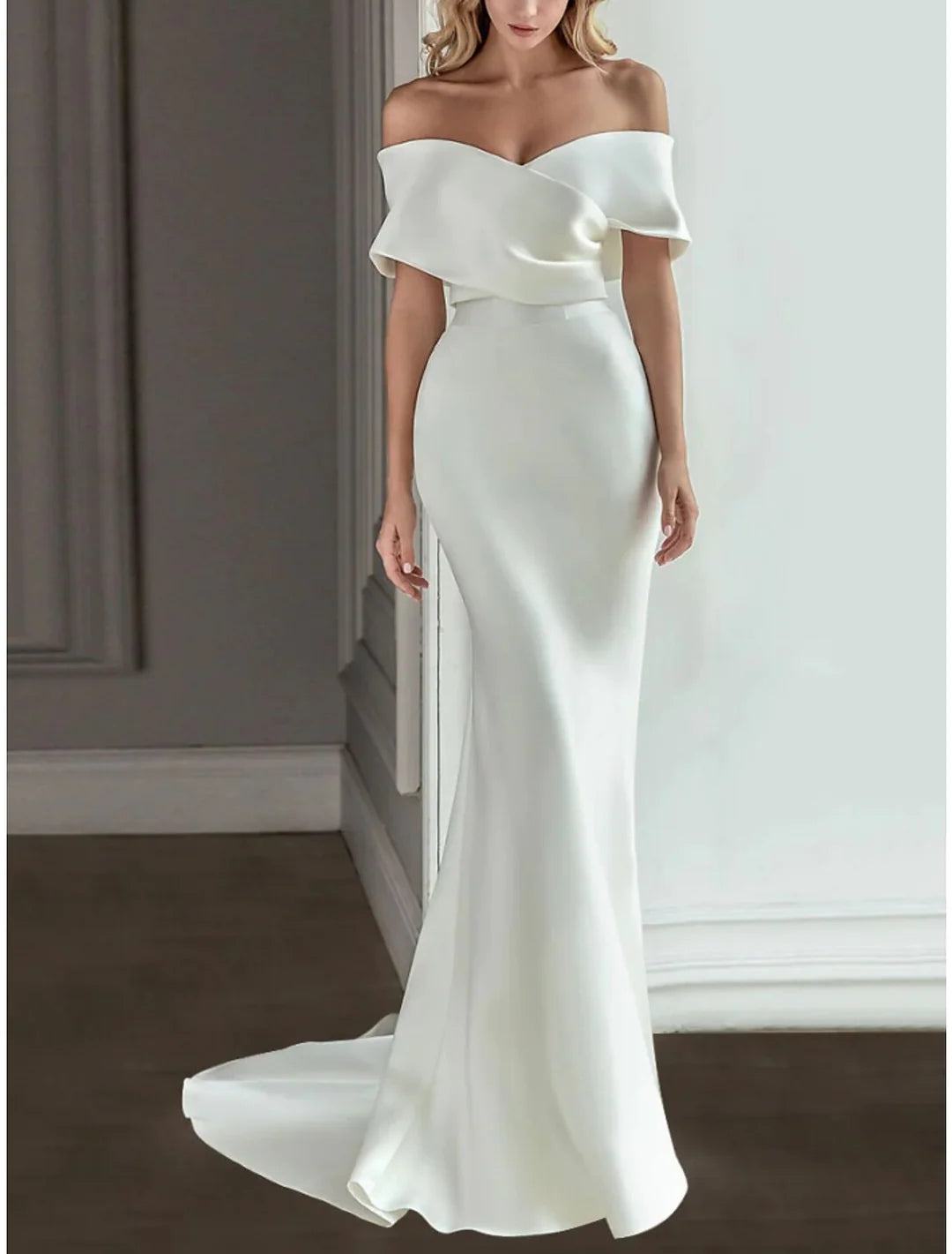 Back view of a model showcasing an A-line off-the-shoulder floor-length wedding dress.