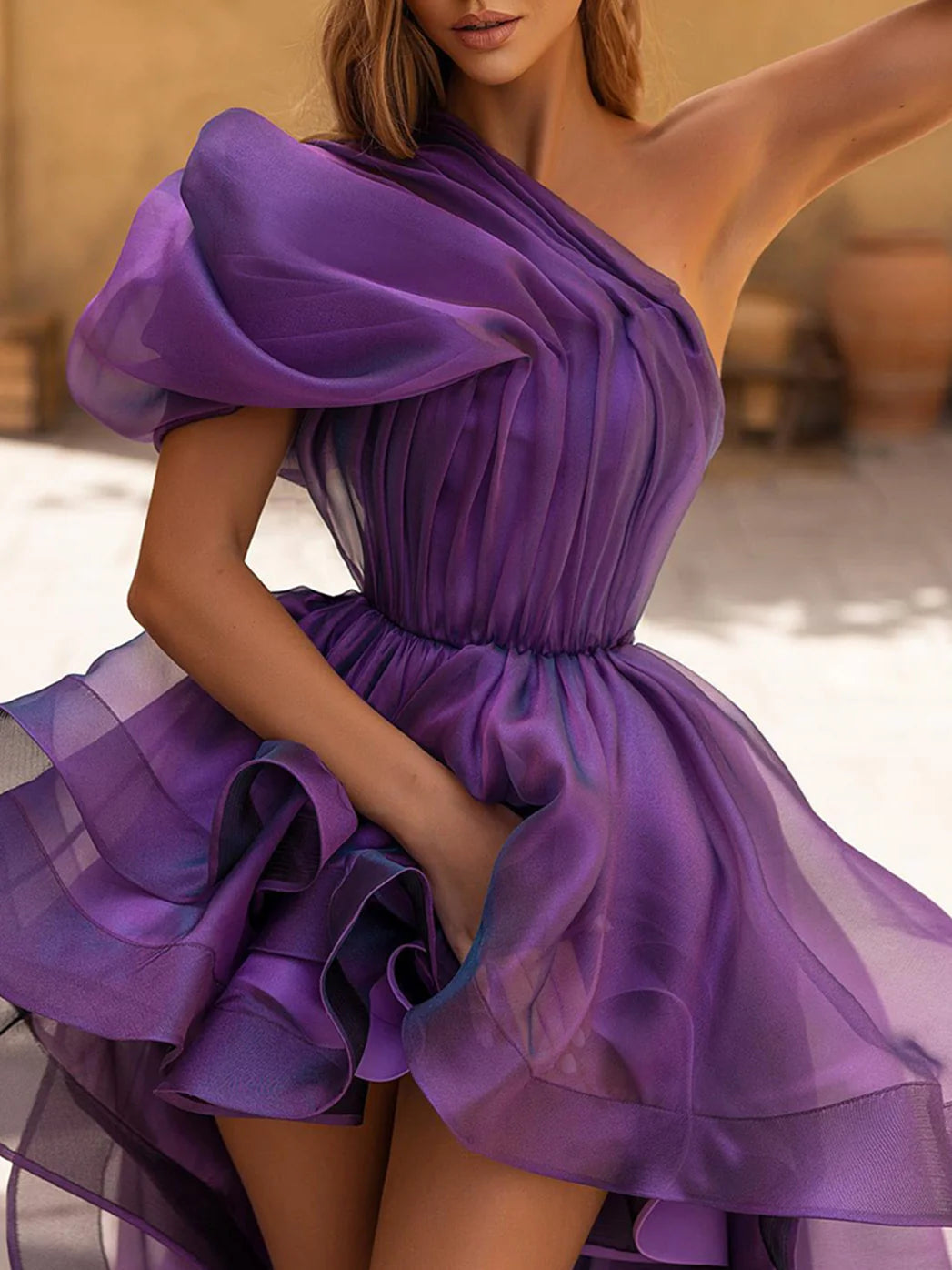Woman posing gracefully in a one-shoulder formal gown.