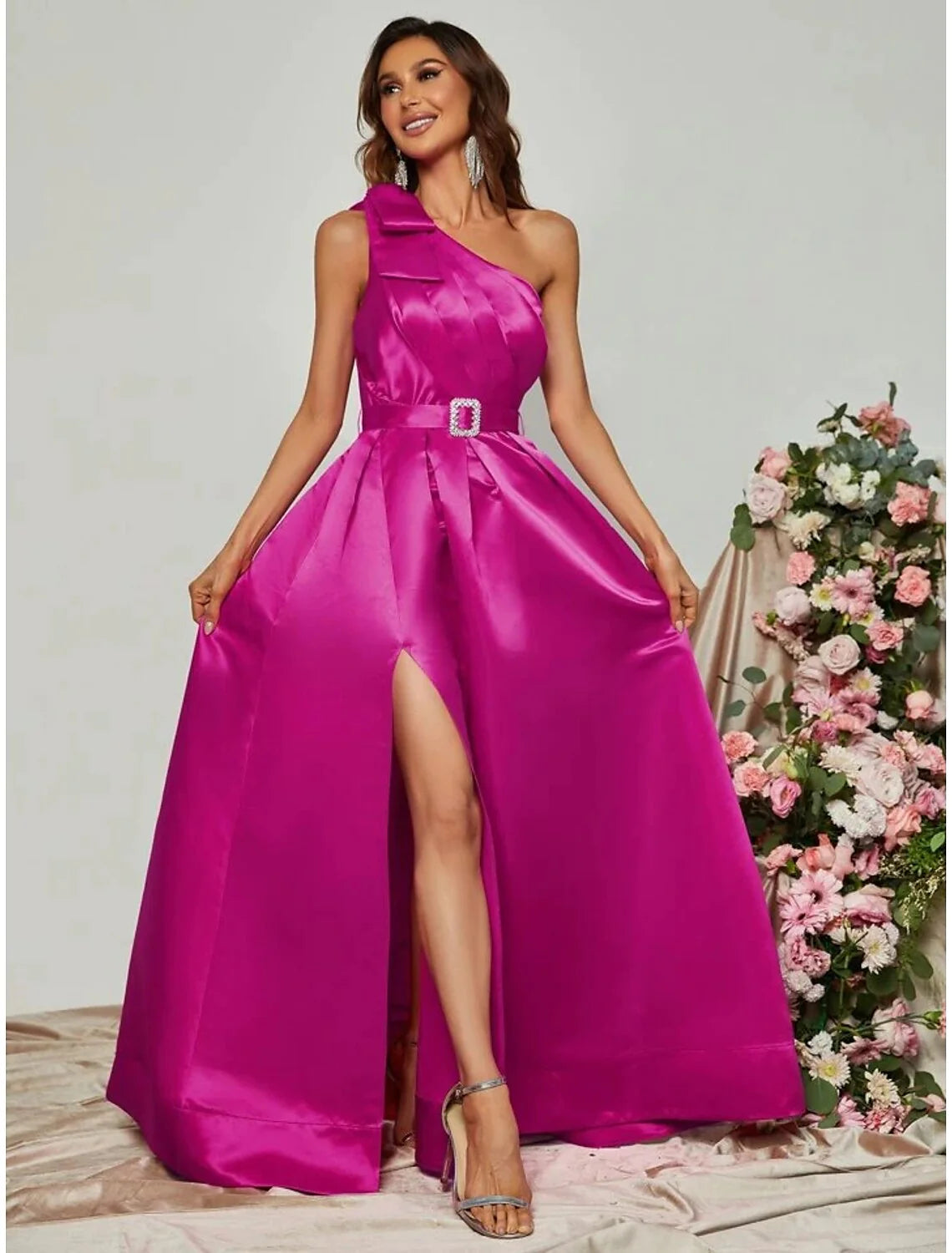 Woman in elegant black one-shoulder A-line satin gown with a high slit, posing gracefully.