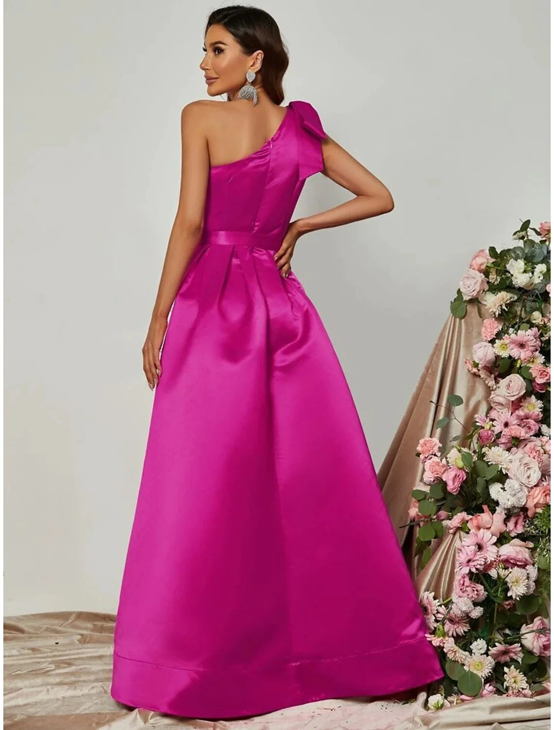 Back view of a woman in a black one-shoulder satin formal dress, showcasing the flowing A-line skirt.