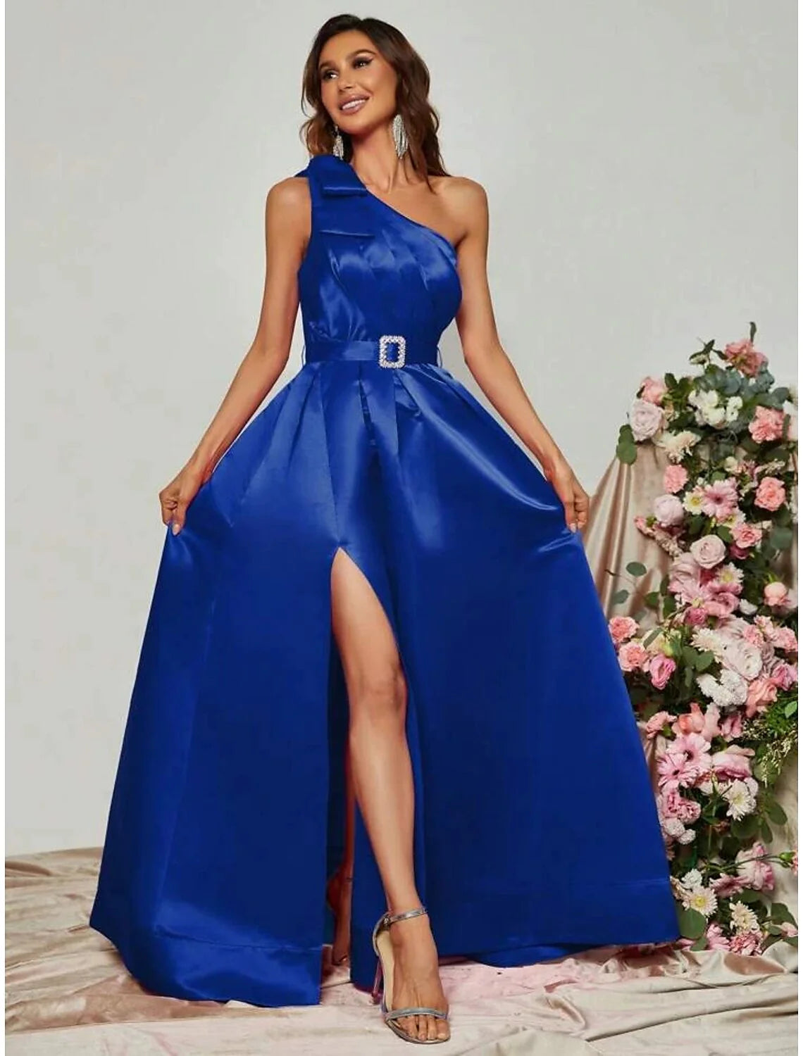 Woman walking in a black one-shoulder A-line gown, showing the movement of the floor-length skirt and slit.