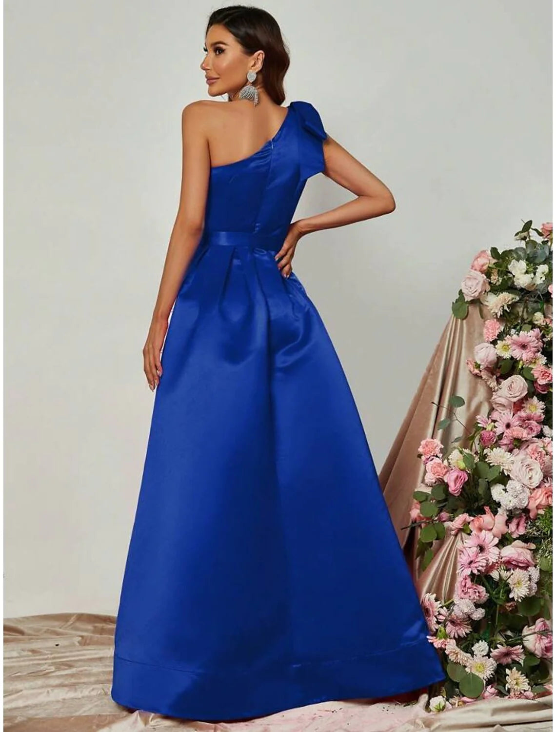 Full length view of a woman in a black one-shoulder satin dress, ready for a formal event.
