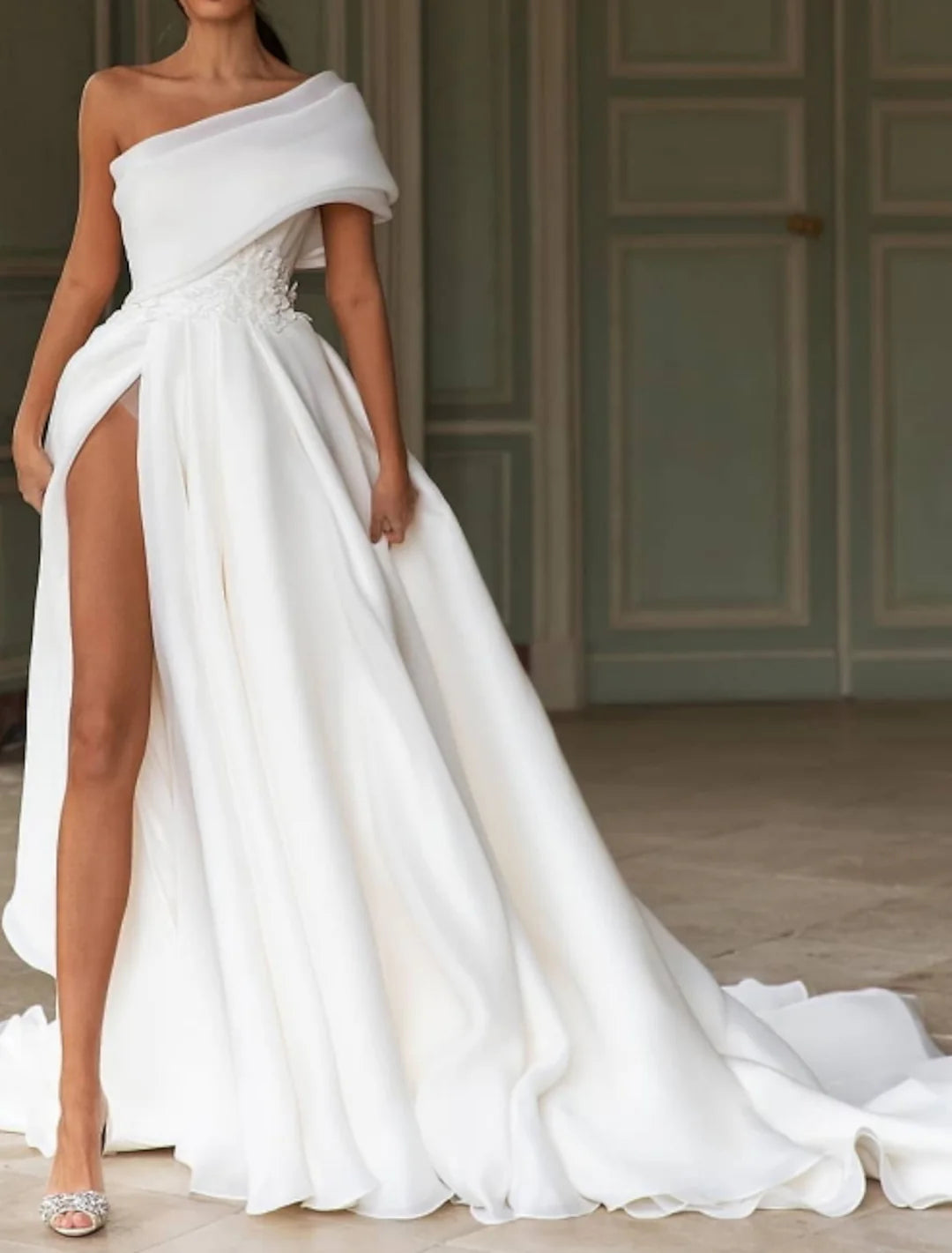 Elegant A-line one-shoulder wedding dress with a court train on a model.