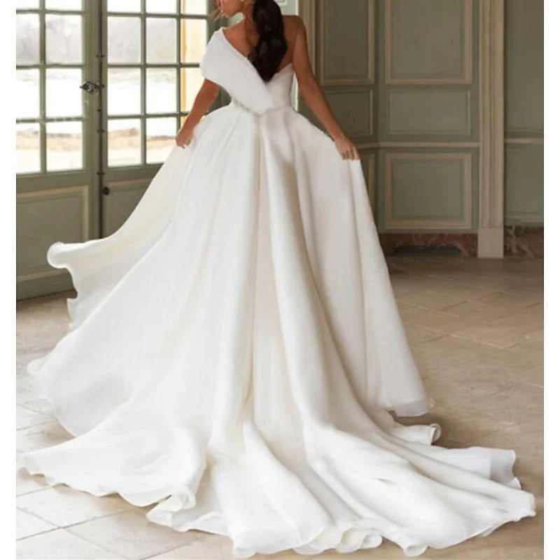 Close-up of the one-shoulder neckline and bodice of an A-line wedding dress.