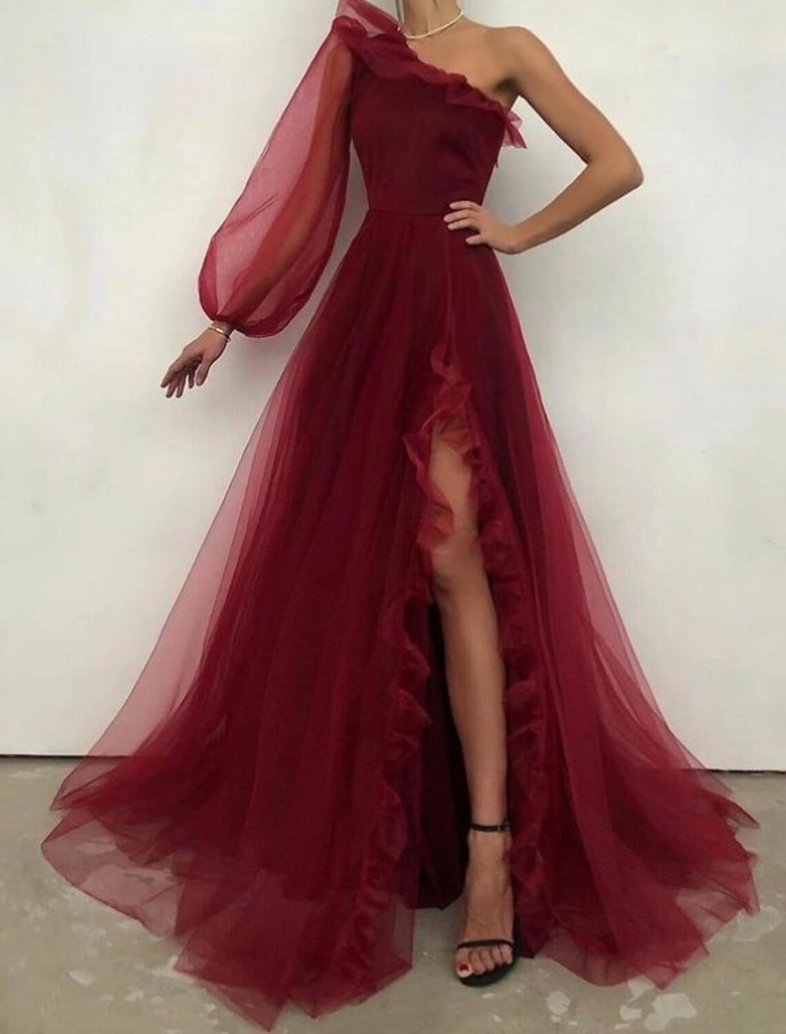 Elegant A-line one-shoulder long sleeve tulle gown with ruffles and sweep train.
