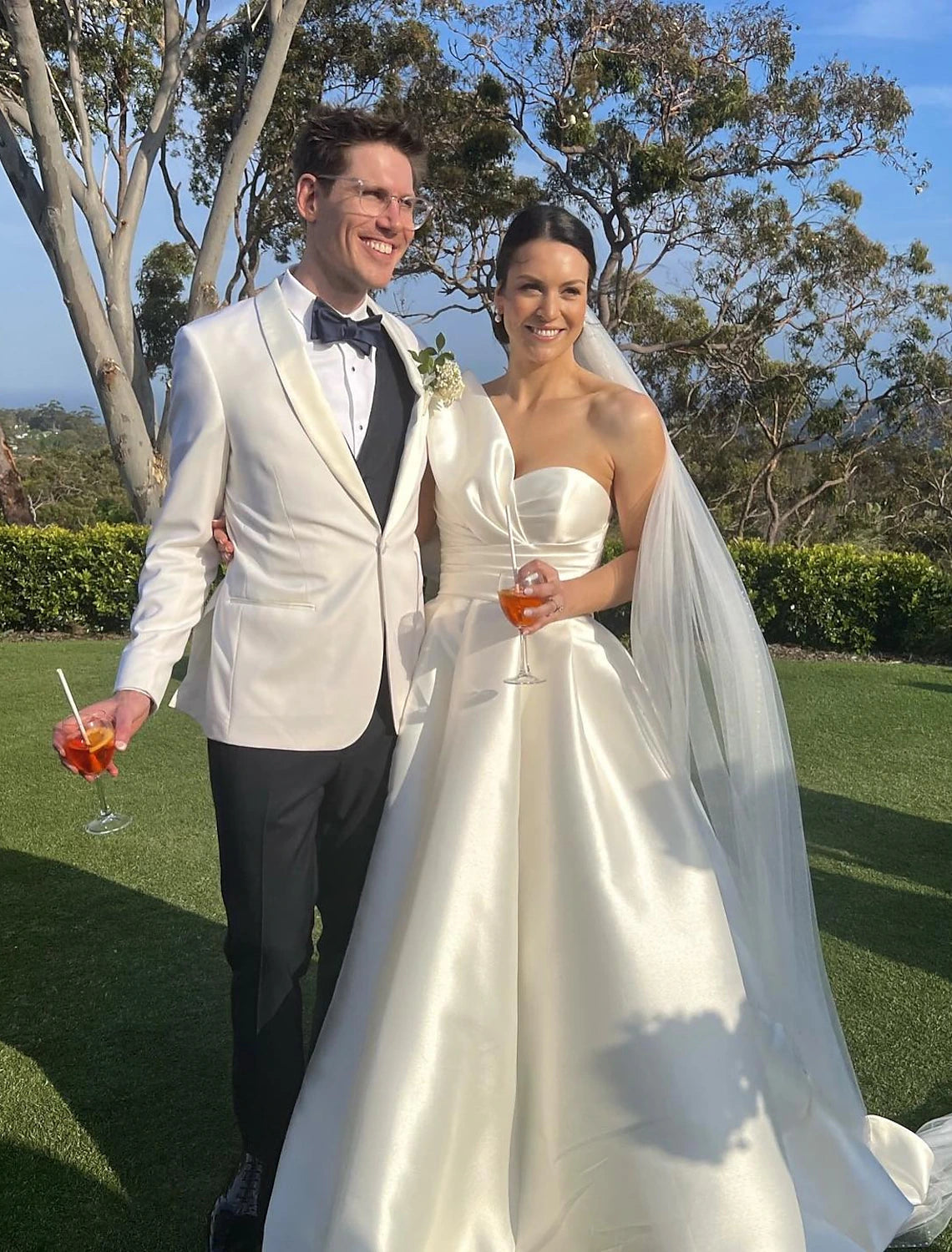 Side view of a formal one-shoulder satin bridal gown, showcasing the sweep train.