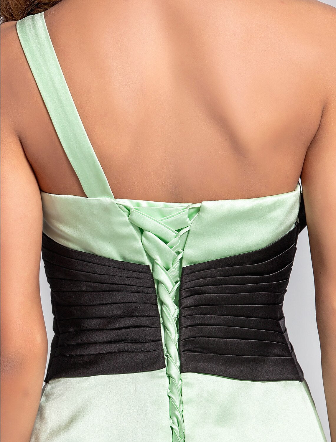 Close-up of crystal brooch on one-shoulder satin bridesmaid dress.