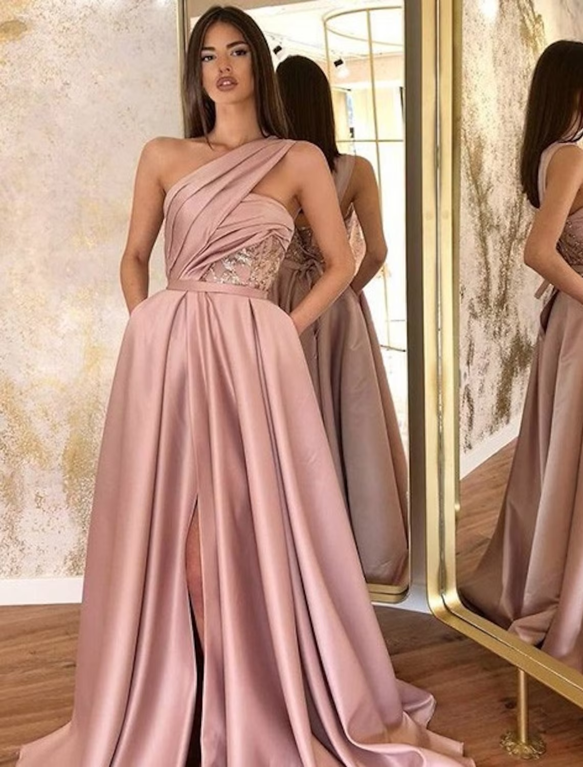 Model wearing an elegant A-line one-shoulder satin evening gown with a ruched slit.