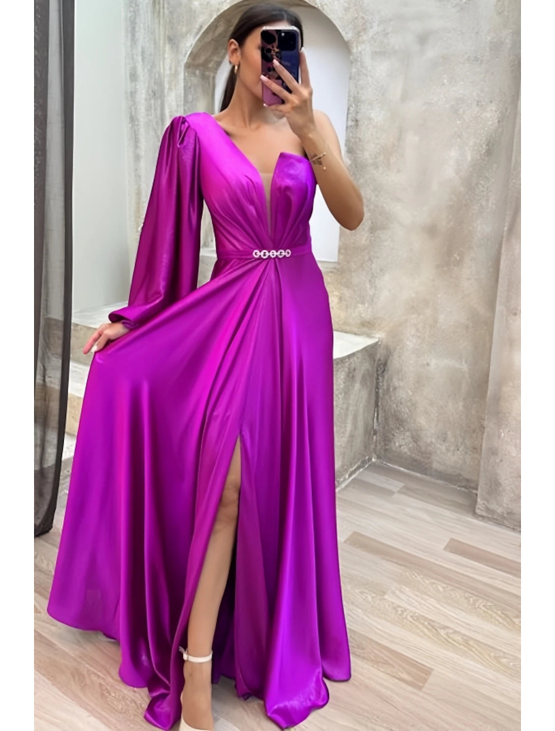 Close-up of the pleated detail and high slit on the satin gown.