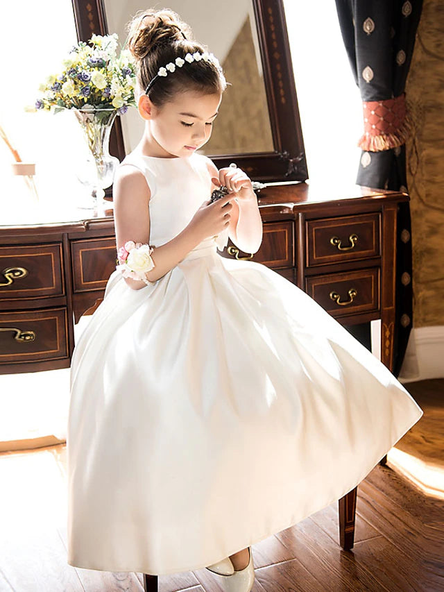 Girl wearing an elegant A-line satin flower girl dress with a bow.
