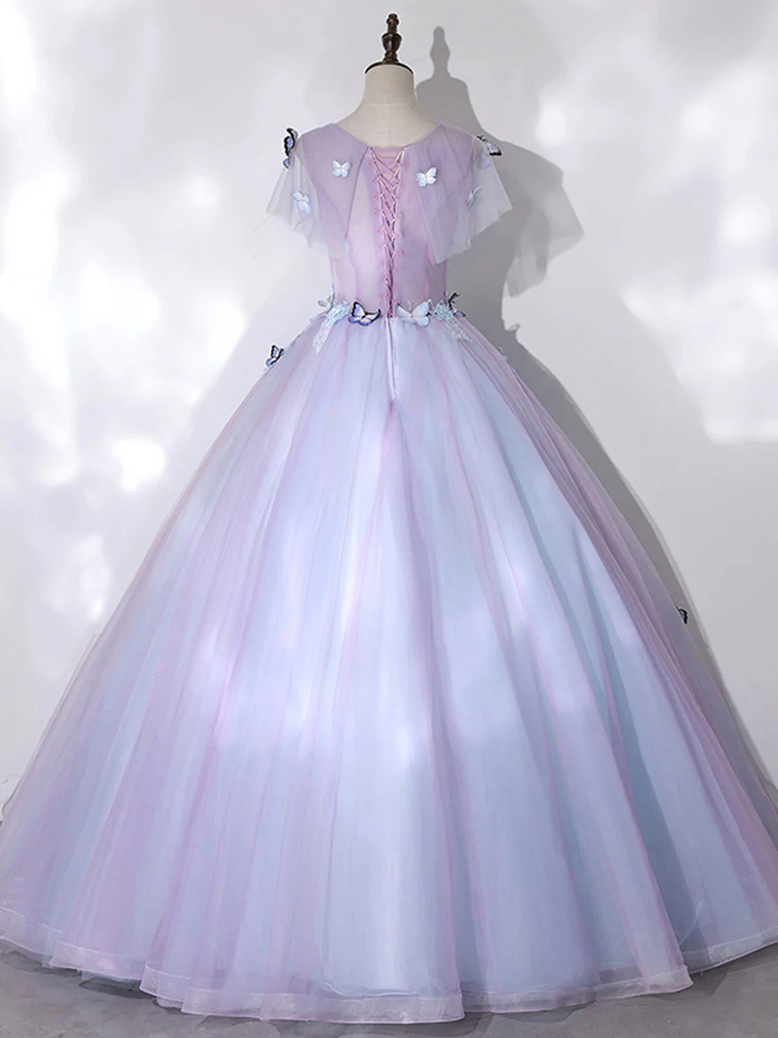 Woman modeling a long A-line formal gown, showcasing the back detail and elegant drape.