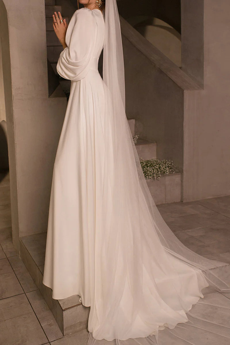 Close-up of the V-neckline and long sleeves of the luxurious satin wedding dress.