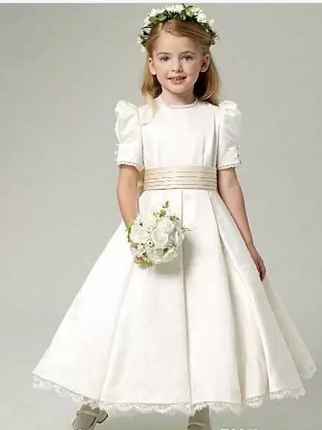 Girl in a white A-line satin flower girl dress with a sash.