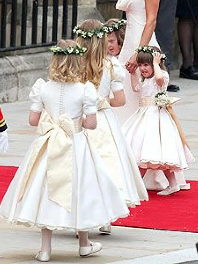Front close-up of the white A-line satin flower girl dress bodice and sash.